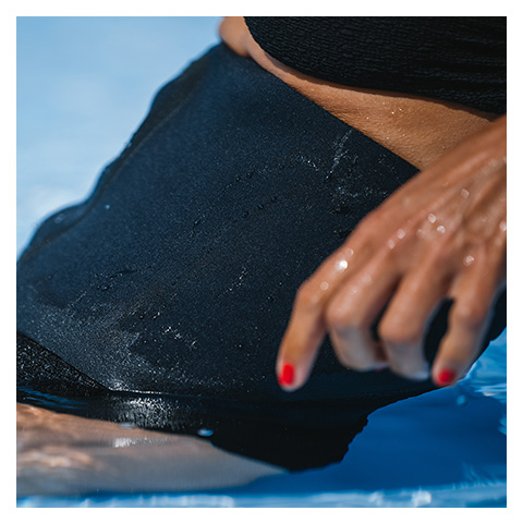 En kvinna som har på sig en svart bråckgördel i poolen när hon badar.