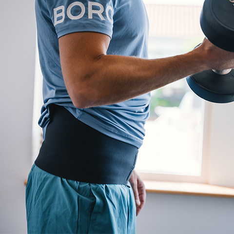 En man tränar på gym med sin stomi och sitt stomibälte med ficka.